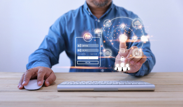 Proving your identity to buy online A man sitting at a table touches a touch screen in front of a mouse and keyboard.