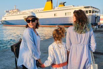 A family walks along a quay and heads towards a large cruise ship moored at the dock