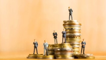 Des piles de pièces sur lesquels sont perchées des figurines humaines