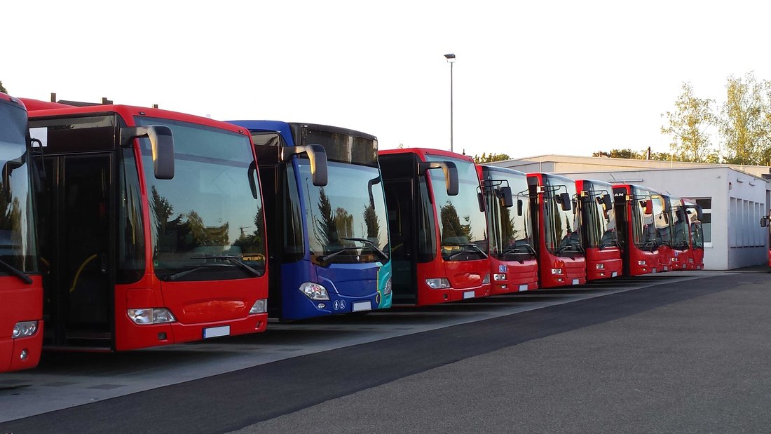 bus-transports-travel.jpg A row of red and black coaches that are parked in a parking lot.