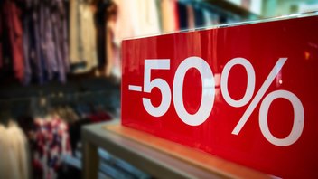 boutique-soldes-achats.jpg Gros plan sur une pancarte de soldes indiquant "-50%" dans une boutique de vêtements.