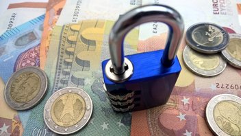 Un cadenas est posé sur un tas de billets et pièces en euros