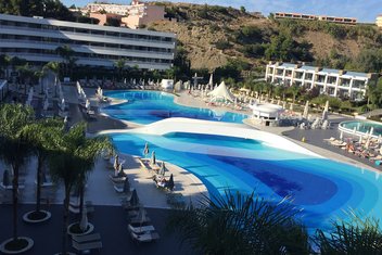 hôtel-avec-piscine Hotel complex with an outdoor swimming pool with sun loungers and palm trees
