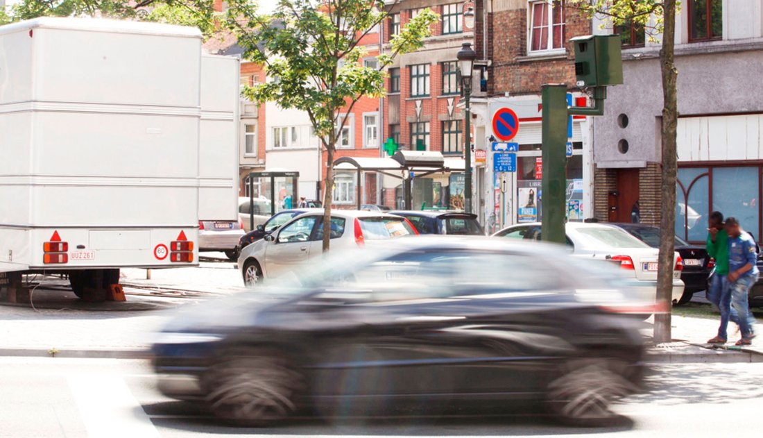 A blurry car drives quickly down a street in a city centre