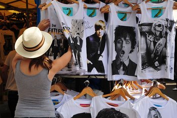 purchase-clothes.jpg A woman looks at T-shirts at a market stall.