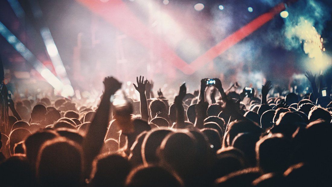 A crowd of people listening and dancing at a concert