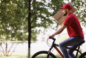 Bicycle delivery person A man rides a bicycle carrying a package on his right shoulder