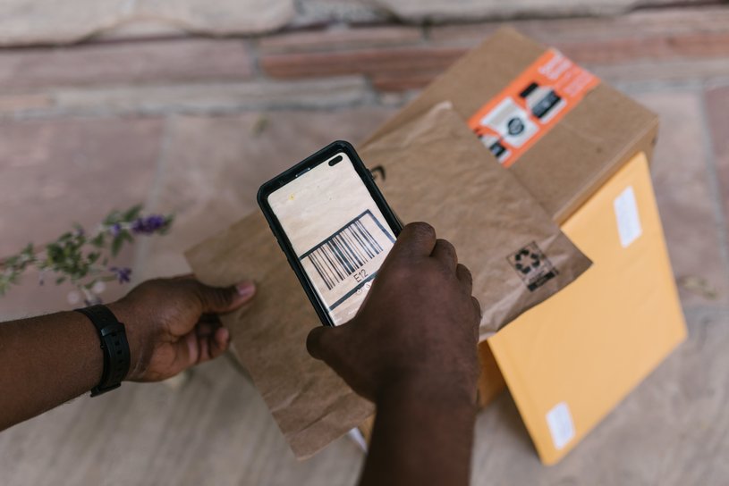 Hands of a delivery person scanning one of the three packages in the image