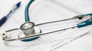 Gros plan sur un stéthoscope posé sur des formulaires médicaux.