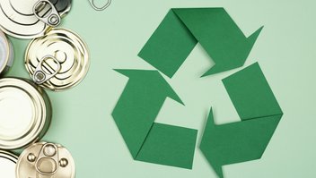 Logo vert du recyclage à côté de boîtes de conserve vides