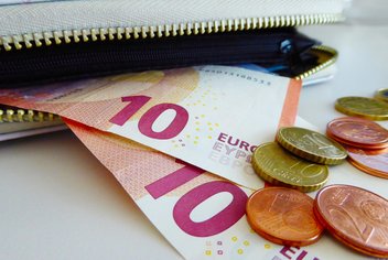 payment-liquid-purchase.jpg Notes and coins come out of a half-open wallet.