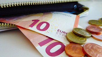 Des billets et des pièces en euros sortent d'un portemonnaie
