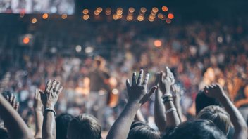 Une foule de personnes lève les mains dans un évènement.
