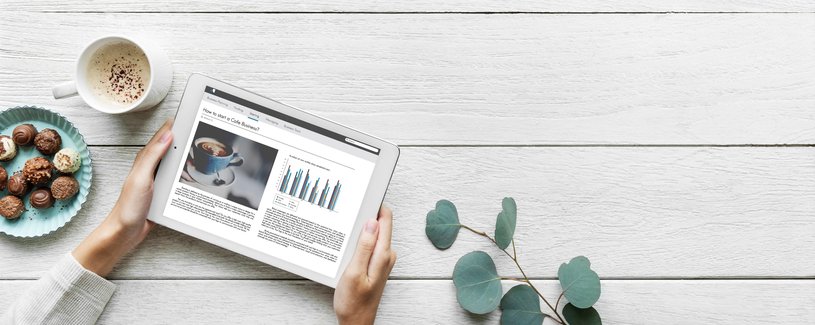 subscription-internet.jpg One person surfs on his tablet, a cup of coffee and chocolate are placed next to it.