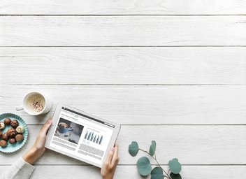 subscription-internet.jpg One person surfs on his tablet, a cup of coffee and chocolate are placed next to it.