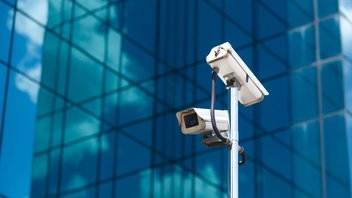 Deux caméras de surveillance sur fond d'un gratte-ciel en verre