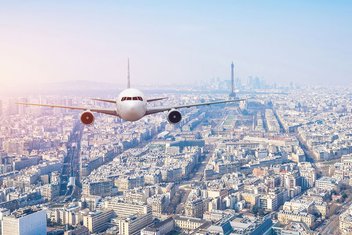 A plane flies over Paris, with the Eiffel Tower in the background
