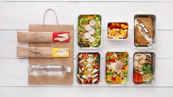 Plats emballés dans de l'aluminium avec deux sets de couverts et une bouteille d'eau en plastique