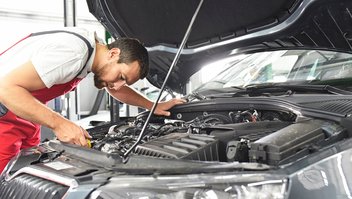 Un mécanicien penché sur une voiture effectue des réparations sous le capot