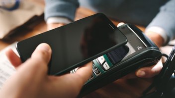 Un téléphone est apposé sur un terminal de paiement pour payer sans contact