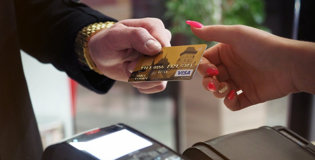 pay-boutique-card-contactless-payment.jpg A man gives his bank card to a woman who holds a bank terminal for payment.