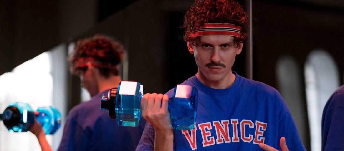 Un coach sportif soulève un haltère devant un miroir