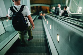 Un homme portant un sac à dos descend des escalators