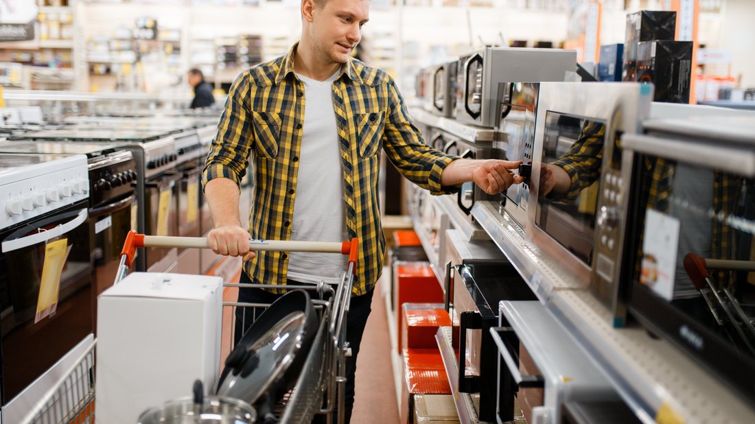 Un homme déambule dans un magasin en regardant les micro-ondes